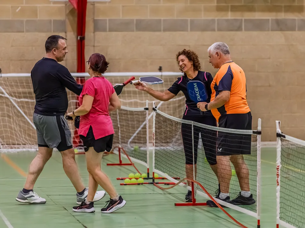 Players shaking hands across the pickleball net after a game