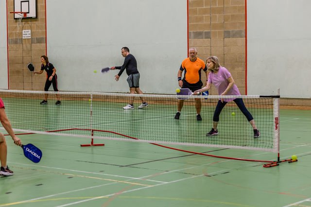 Four players preparing for a rally during indoor pickleball matchplay