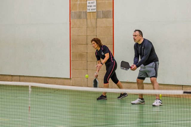 Two pickleball players moving together during a doubles rally