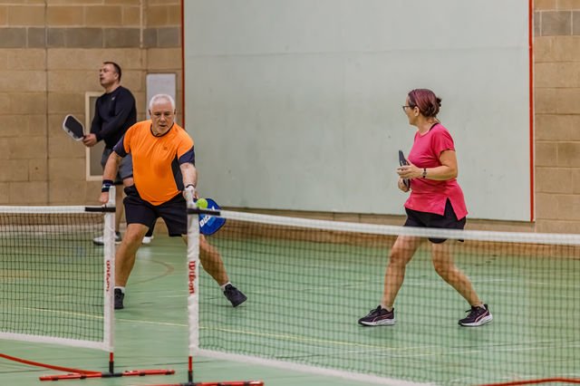 Players enjoying a mixed doubles rally on an indoor pickleball court